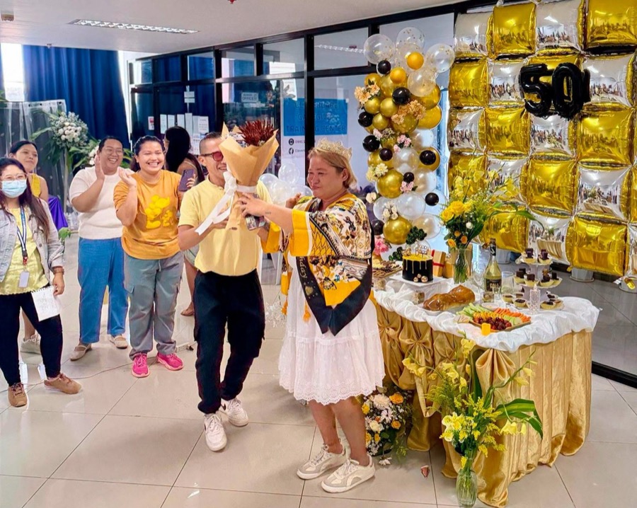 Student receiving a bouquet, CleverCare Caregiver Training Center signage visible in background